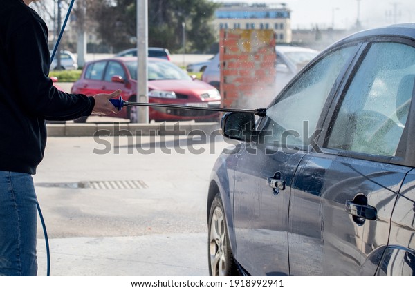 Car washing. Man cleaning his car using high pressure
water. 