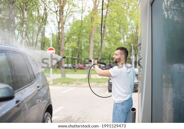 Car
washing. Man cleaning car using high pressure
water.