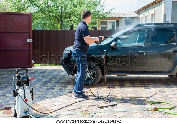 Car washing. A man washes a car with a
portable washer with a high-pressure
hose