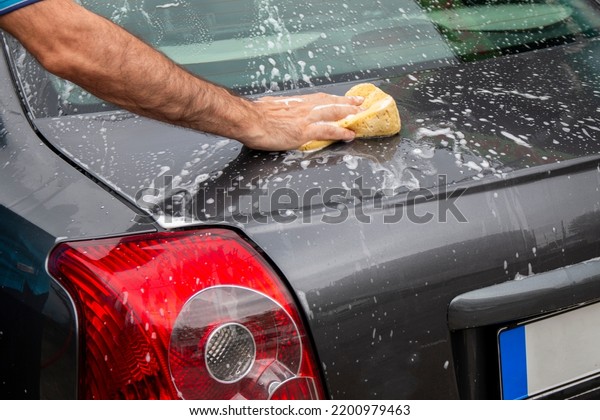 Car washing.  Mature man cleaning automobile with\
foam.Vehicle covered with foam shampoo chemical detergents during\
carwash self service
