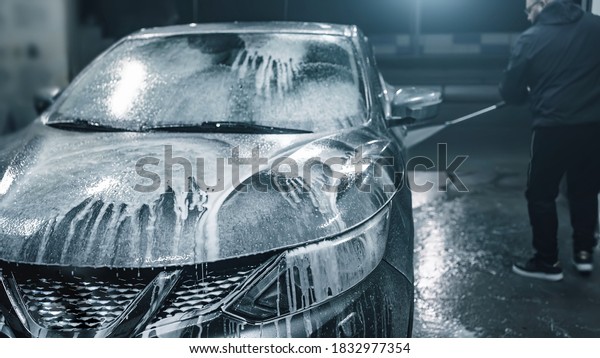 Car washing at night. Man cleaning his car\
using high pressure water at\
self-service