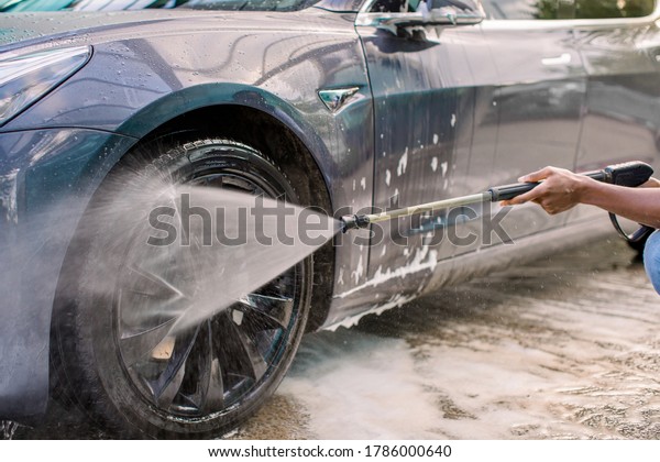 Car washing outdoors.\
Car washing with soap and high pressure water. Wheel alloy cleaning\
at car wash station with foam and high pressure water jet. Washing\
rims.