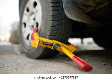 Car wheel blocked by wheel lock. Illegal parking of automobile. Wheel of automobile was locked with clamped tire boot. Parking violations. Illegally parked car. - Shutterstock ID 2175577817