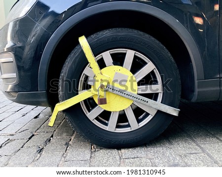 Car wheel blocked by wheel lock because illegal parking violation Wheel lock for anti-theft with the car on the road or concrete floor.