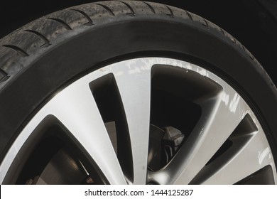 Car wheel closeup. Damaged alloy rim with black thin tire. Bad driver concept.