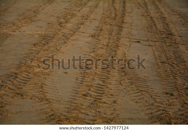 Car wheel marks on\
the sand Overlapping