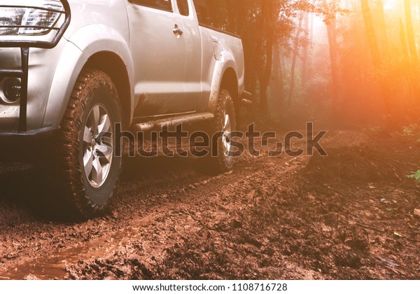 Car wheel on a dirt road in forest. Off-road tire\
covered with mud,