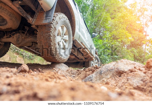 Car wheel on a dirt\
road. Off-road tire covered with mud, dirt terrain. Outdoor,\
adventures and travel. Car tire close-up in a countryside\
landscape. Four wheel truck in\
mud.