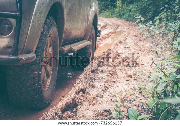 Car
wheel on a dirt road. Off-road tire covered with mud, dirt terrain.
Outdoor, adventures and travel. Car tire close-up in a countryside
landscape with a muddy road. Four wheel truck in
mud.
