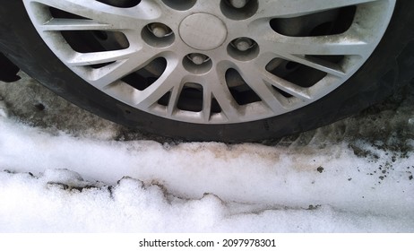 Car wheel on dirty messy snow. Mud, salt and chemicals on road in winter. Ecology problem in city. Protection and wash vehicle concept. Environment conversation. Driving. Auto hubcap. Climate change.