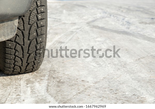 A car wheel on a slippery winter road.\
Close- up of studded rubber on ice. Dangerous driving conditions.\
Icy road with tracks from the wheels of\
cars