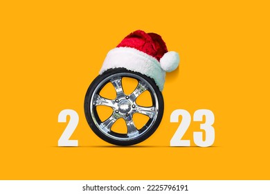 Car wheel in a Santa Hat on a bright orange background. Ccopy space. Place for text. New Year card. Festive background. - Powered by Shutterstock