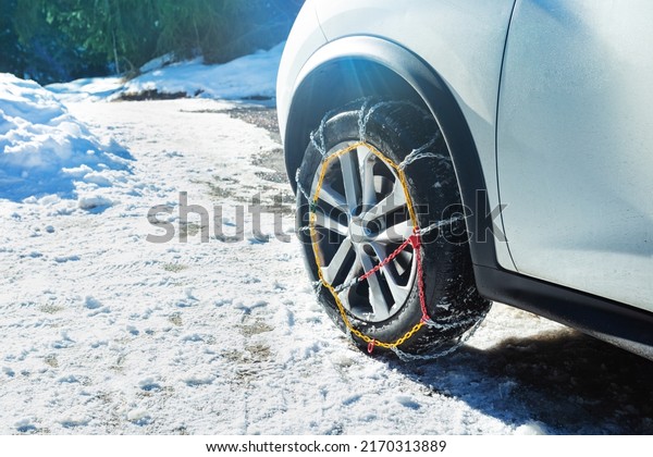 Car wheel with winter chains for snow and ice road\
on it close-up image
