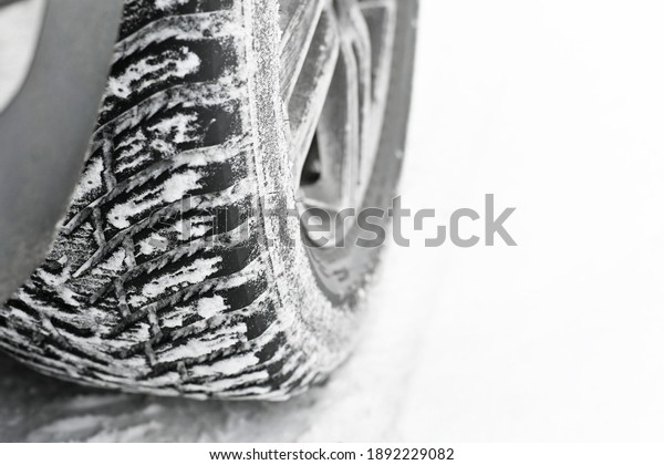 car wheel with winter studded tires on a snowy\
road close-up