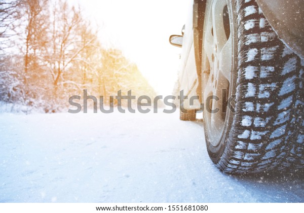 Car wheel with winter\
tire on snow road
