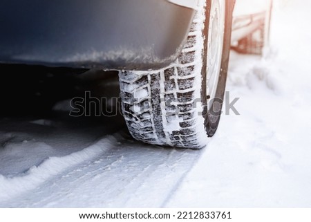 A car wheel with winter tires and a footprint on a snowy road. Snow drifts, ice, insurance event concept