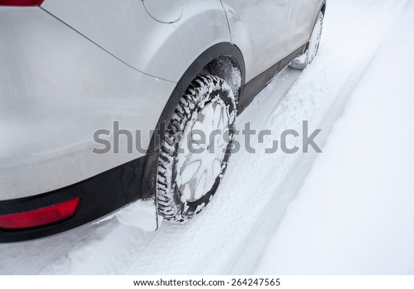 Car wheel\
in winter tyre driving on snow, close\
up