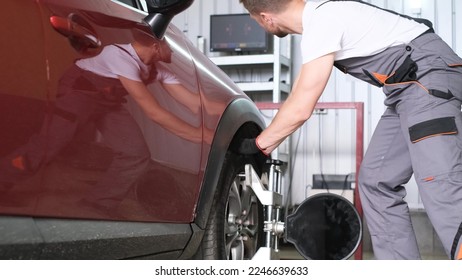 Equipo de alineación de las ruedas de automóvil en un soporte de una estación de reparación. El mecánico automático ajusta el auto para diagnósticos y ajustes.