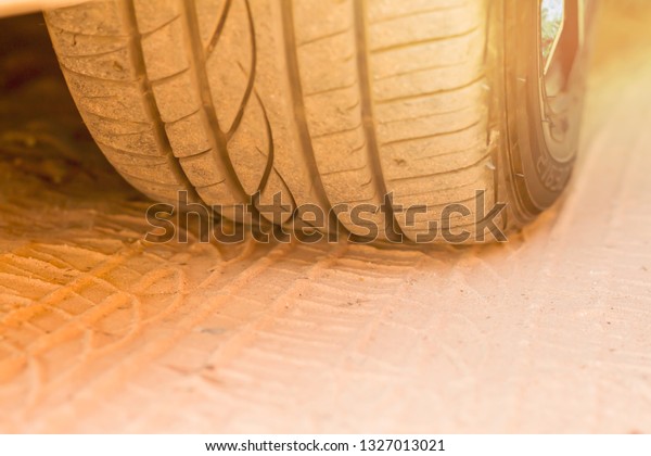 Car wheels and\
rubber marks on sandy\
ground