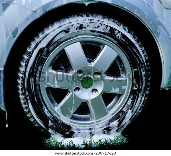 car wheel.Washing the car a jet of pure water on a\
background of green water.