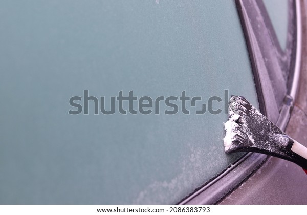 the car window\
is covered with ice, a woman cleans the frozen window with a\
scraper from ice, the first\
frosts