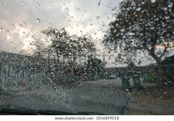 Car window covered with rain droplets, rainy weather\
during spring season. Raindrop on the car glass with blurred\
background. Rain drops on the car glass. Water drops on the car\
glass.  