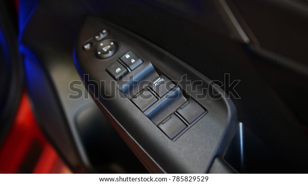 Car window opening\
panel with five buttons. Image in closeup of a door control panel\
in a modern car. Arm rest with window control panel, door lock\
button, and mirror control.