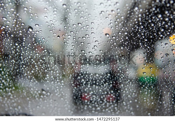 car window with rain drops driving in\
rain.Traffic jam background\
blurred