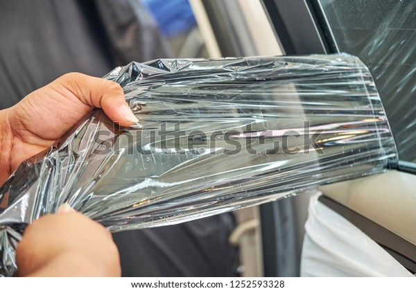Car window tinting installation\
and film removal on side window. Professional hand gently carefully\
grab the corner and peel it from the surface of glass.\
