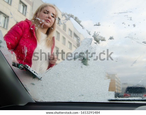 car\
windshield cleaning. girl cleans snow from a\
car