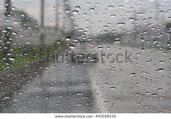 Car windshield with rain drops during storm and blurred\
stoplights. Shallow depth of field with focus on center of the\
windshield 