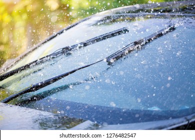 Car Windshield With Rain Drops And Frameless Wiper Blade Closeup