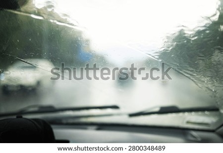 Car windshield with rain drops and frameless wiper blade closeup. 
