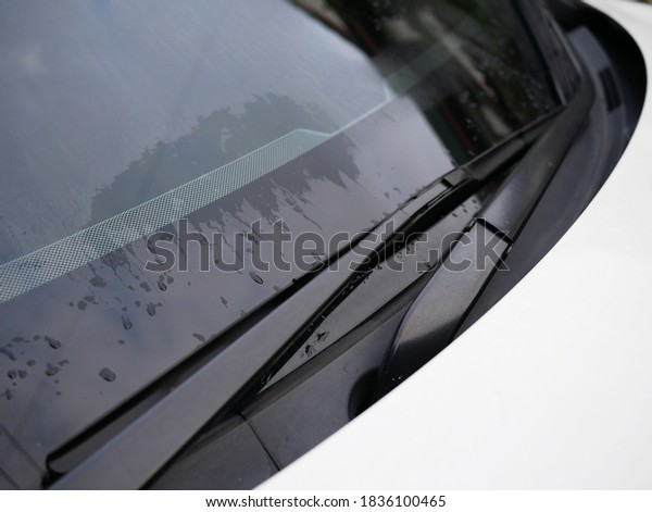 car\
windshield with rain water drops on white\
car.