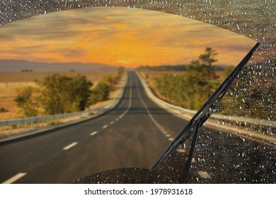 Car windshield wiper cleaning water drops from glass while driving