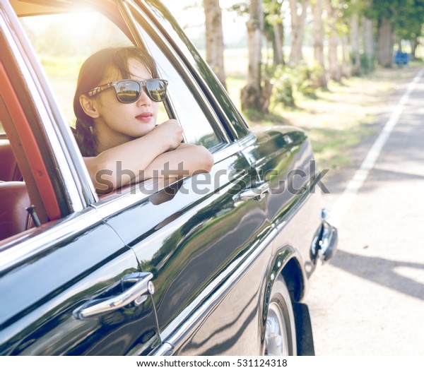 Car woman happy in old  retro\
vintage car. Young woman driving on road trip on beautiful sunny\
summer day. Pretty mixed race Asian / Caucasian female\
model.\
\
