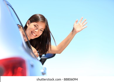 Car Woman Happy Waving Smiling At Camera Popping Head Out The Window. New Car, Road Trip Vacation Or Drivers License Concept. Beautiful Young Mixed Race Chinese Asian / White Caucasian Woman.