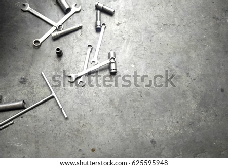 Car workshop tools left lying around on the floor. Workshop floor greasy and dirty.
