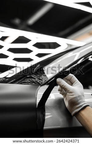 Car wrap application changes vehicle appearance. Full Panel Car Vinyl Wrapping. Large-scale vinyl wrap installation transforms the vehicle exterior with matte black film
