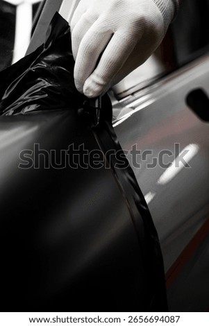 Car wrap application changes vehicle appearance. Full Panel Car Vinyl Wrapping. Large-scale vinyl wrap installation transforms the vehicle exterior with matte black film