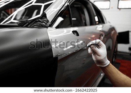 Car wrap application changes vehicle appearance. Full Panel Car Vinyl Wrapping. Large-scale vinyl wrap installation transforms the vehicle exterior with matte black film