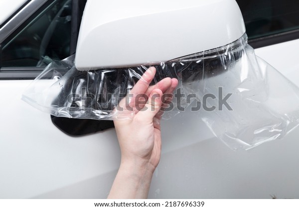 Car wrapping specialist putting transparent vinyl\
film on car hood.Applying a protective film to the car for protect\
car paint.