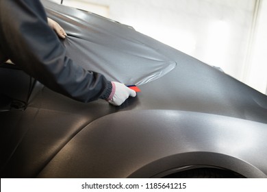 Car Wrapping Specialist Putting Vinyl Foil Or Film On Car. Selective Focus. 