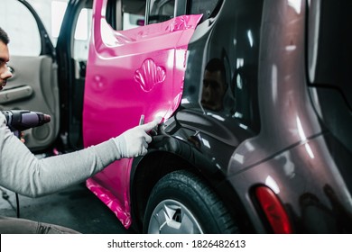 Car wrapping specialist putting vinyl foil or film on car. Selective focus.
