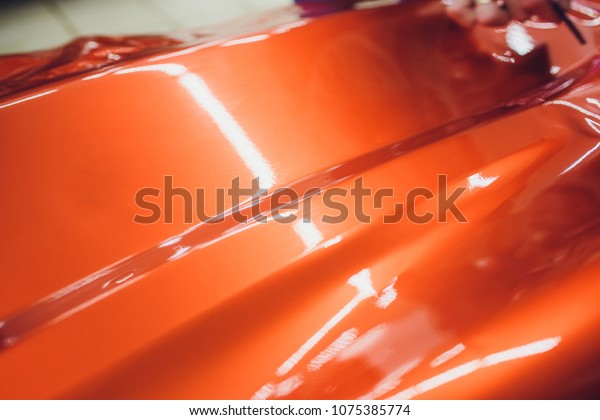 Car wrapping specialist putting vinyl foil or\
film on car wrapping protective film yacht, boat, ship, car, mobile\
home. orange film hand\
pulls