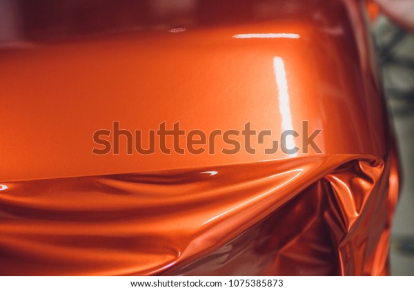 Car wrapping specialist putting vinyl foil or\
film on car wrapping protective film yacht, boat, ship, car, mobile\
home. orange film hand\
pulls
