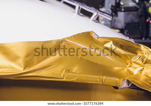 Car wrapping specialist putting vinyl\
foil or film on car wrapping protective film yacht, boat, ship,\
car, mobile home. yellow gold film hand\
pulls
