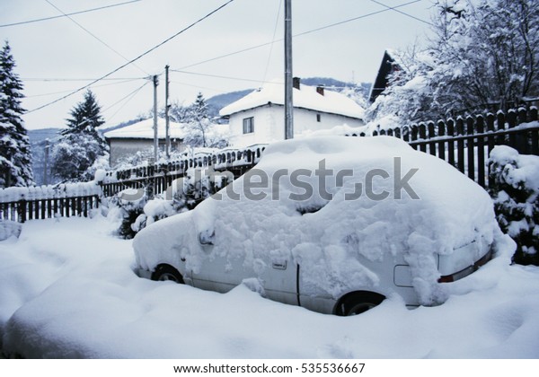 Car in yard covered in snow

