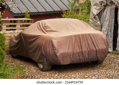 A Car In The Yard Of A Private House Covered With A Tarp