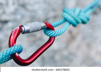 carabiner hook with a climbing rope on rocky background. Climbing concept